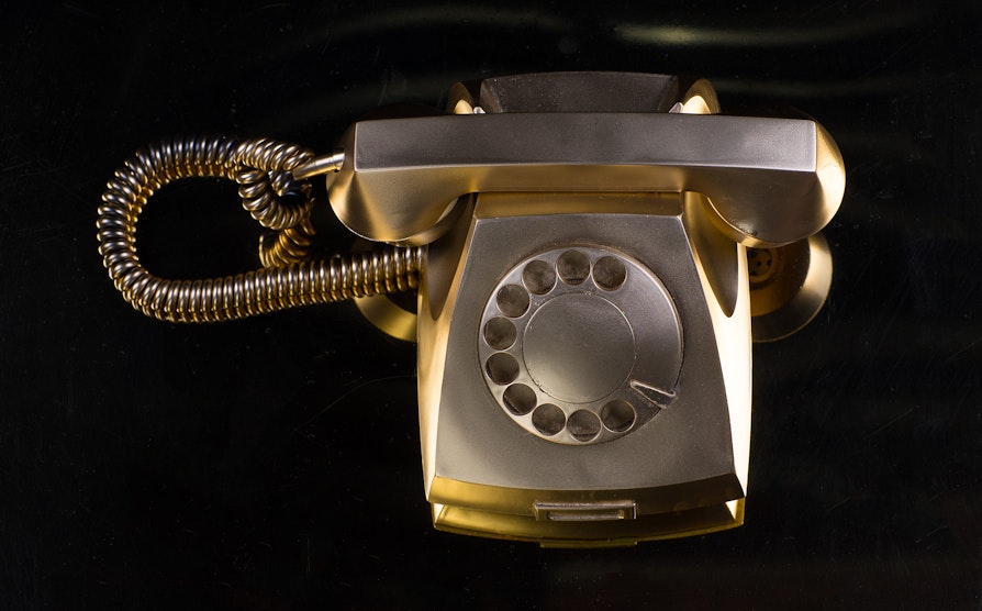 Gullfarget gammel telefon med svart bakgrunn