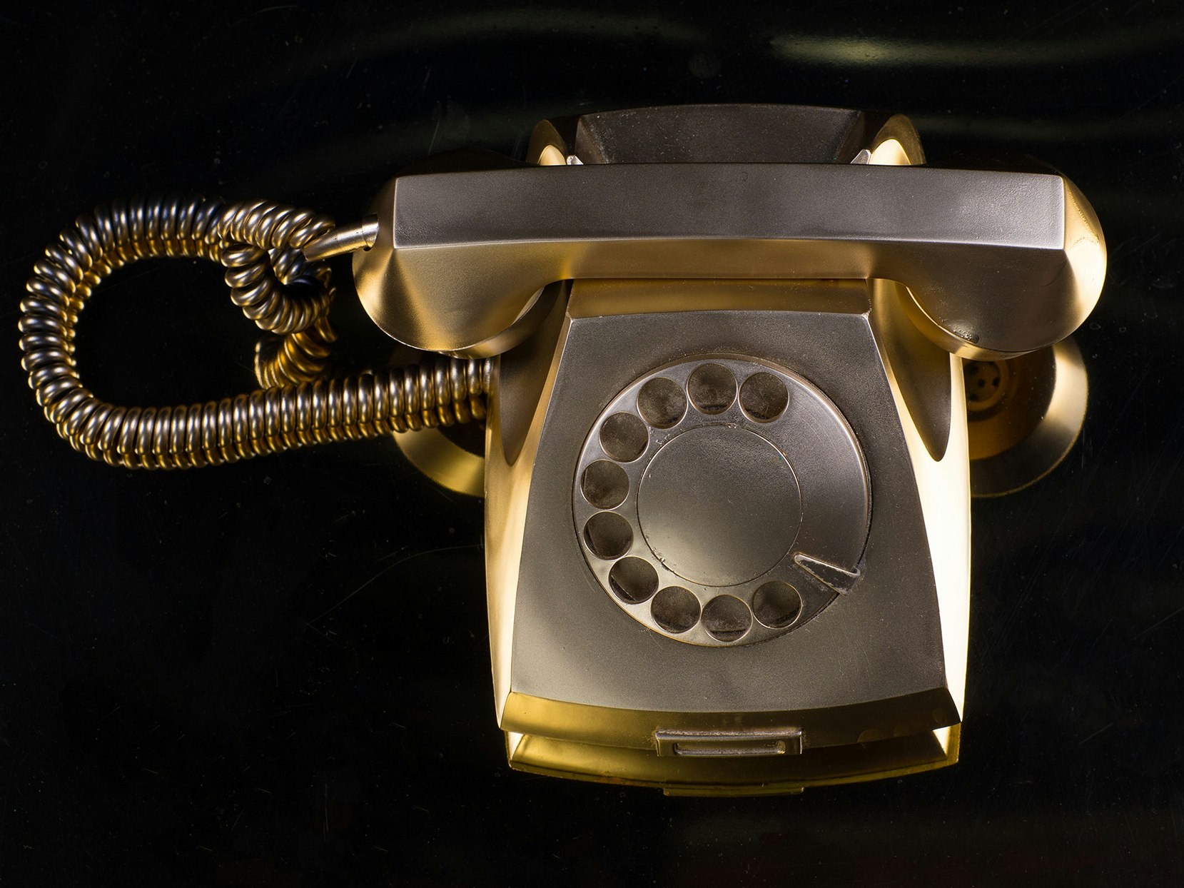 Gullfarget gammel telefon med svart bakgrunn