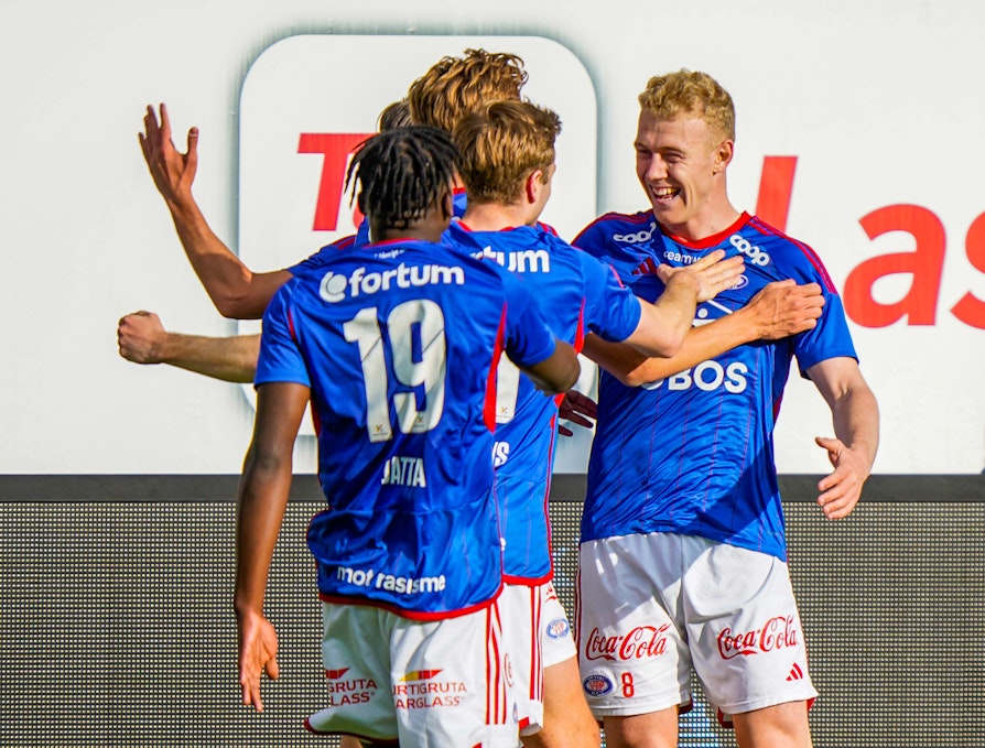 Fotballspillere i blå drakter feirer scoring.