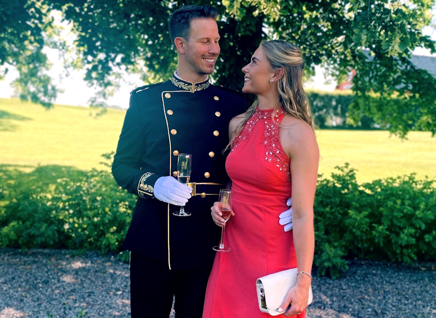 Bilde av par, mann og kvinne i 20-årene, begge pyntet. Sommerlige omgivelser og festlig anledning.