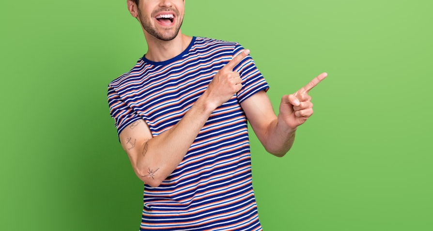 Mann i kortermet stripete genser som er glad og peker opp med pekefingrene