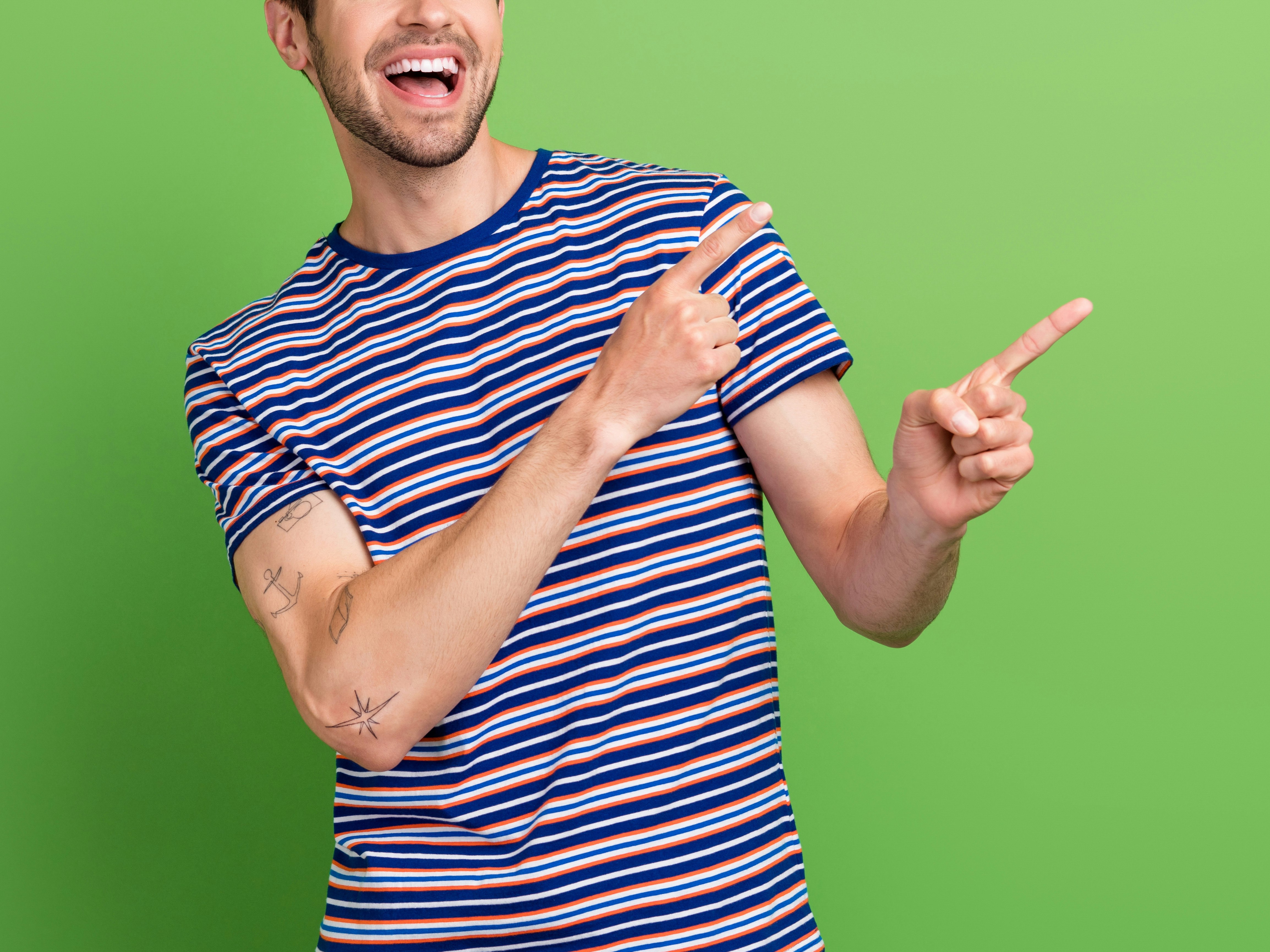 Mann i kortermet stripete genser som er glad og peker opp med pekefingrene