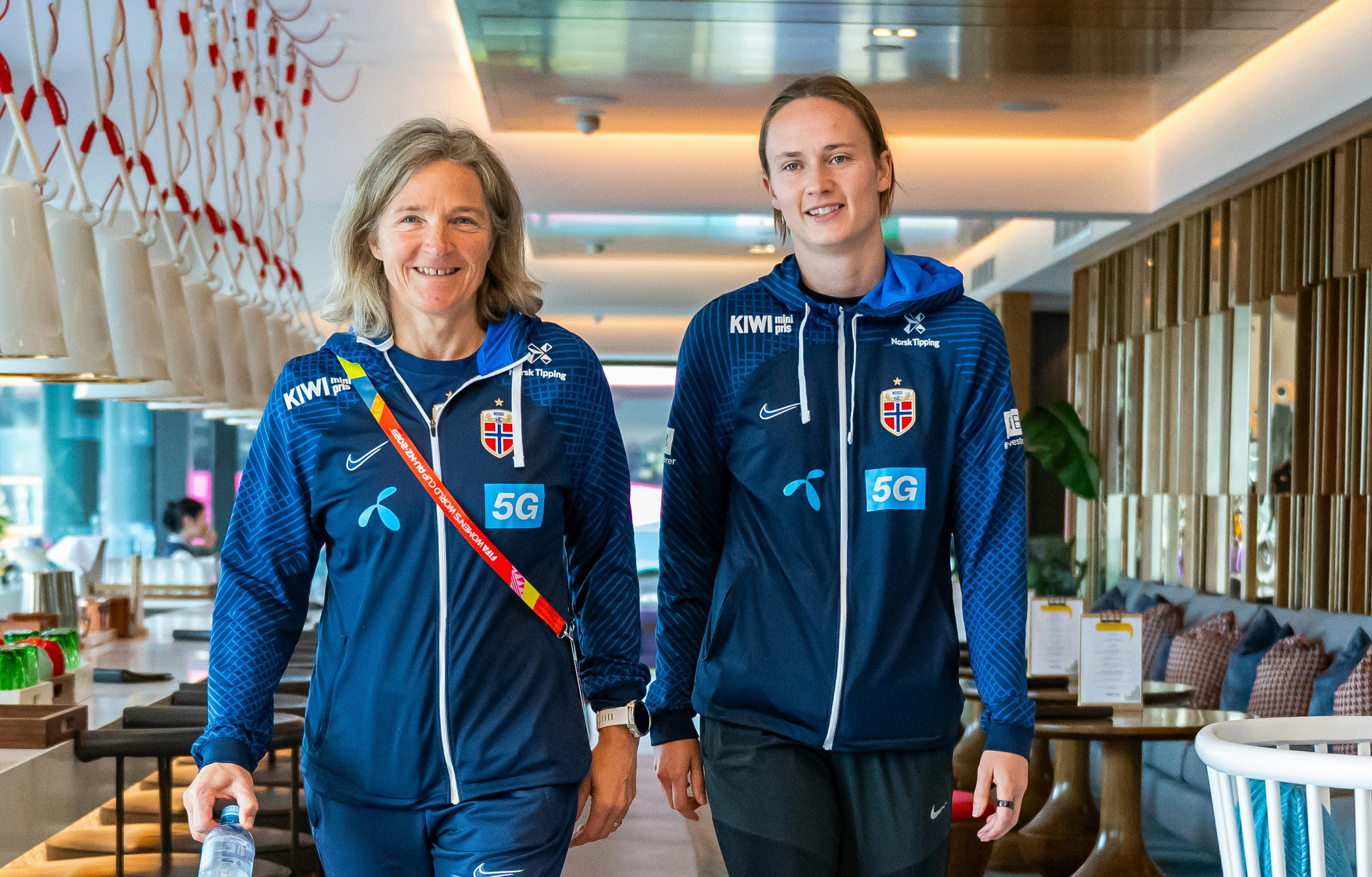 Norges landslagstrener Hege Riise og spiller Caroline Graham Hansen kommer gående i blå treningsdresser.