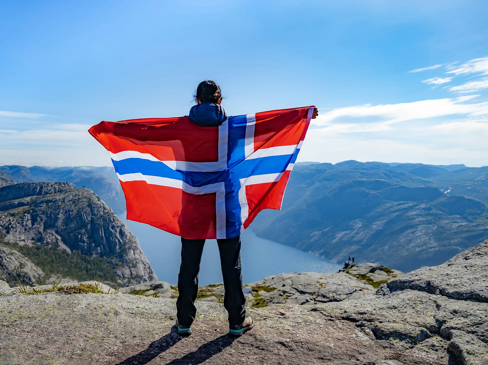 Kvinne som holder et norsk flagg på toppen av et fjell