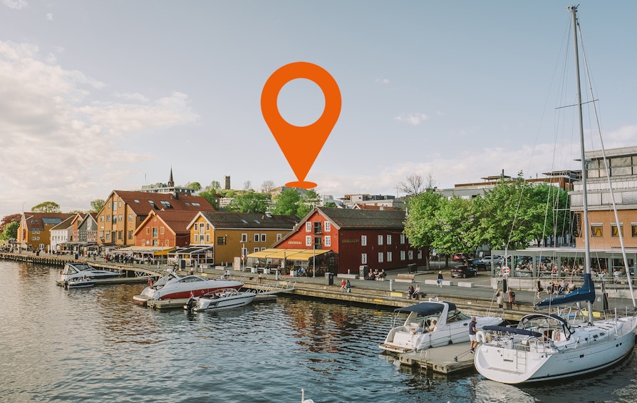 Bilde av bryggeområdet i Tønsberg sommerstid. Båter fortøyd, mennesker i gatene bak.