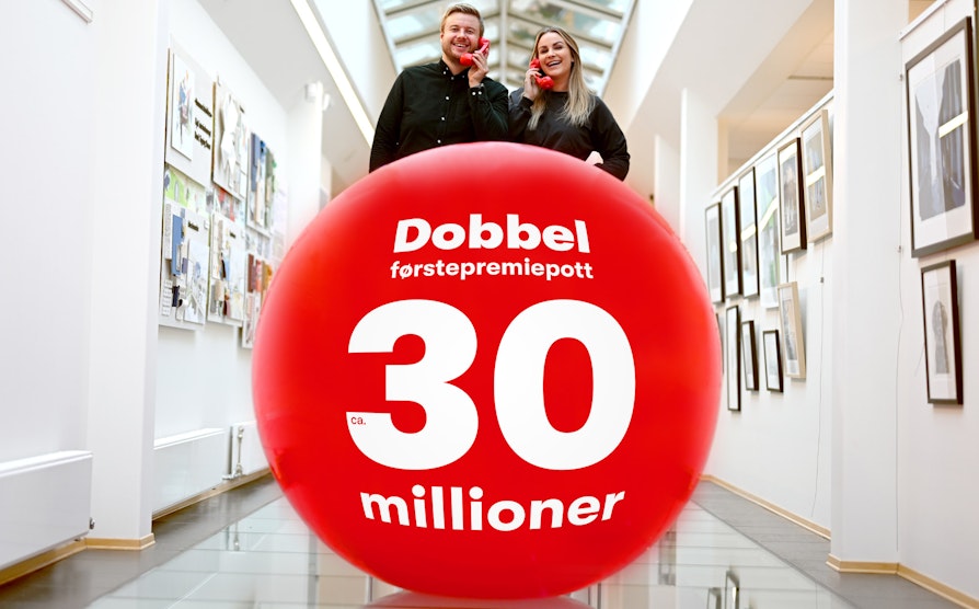 Trekningsredaktørene Lars Hulleberg og Pie Skagsoset Norseng står bak en stor rød ball med Lotto-tekst og holder hvert sitt røde telefonrør.