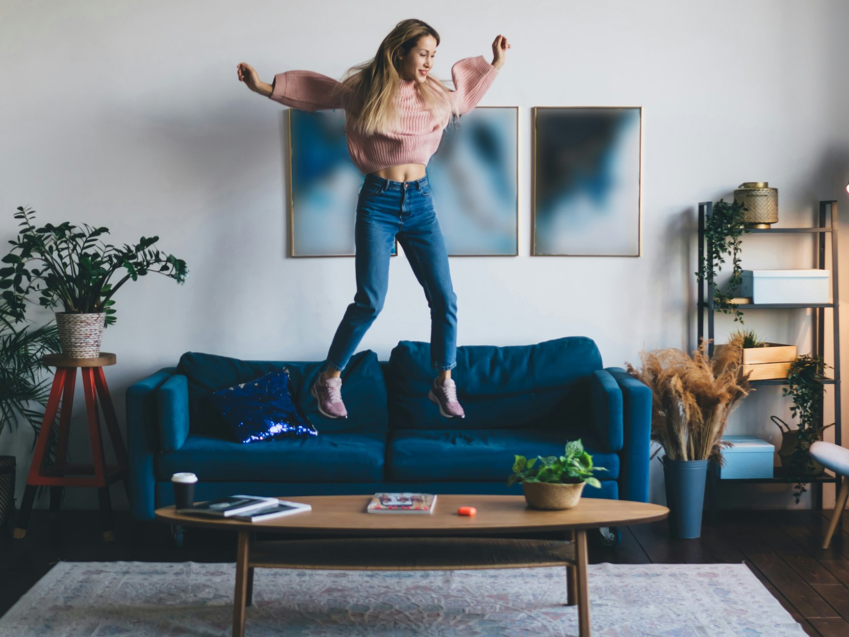 Bilde av ung kvinne som hopper i sofaen i en leilighet.