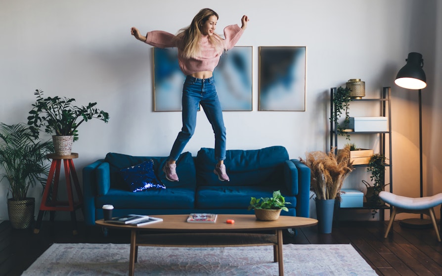 Bilde av ung kvinne som hopper i sofaen i en leilighet.