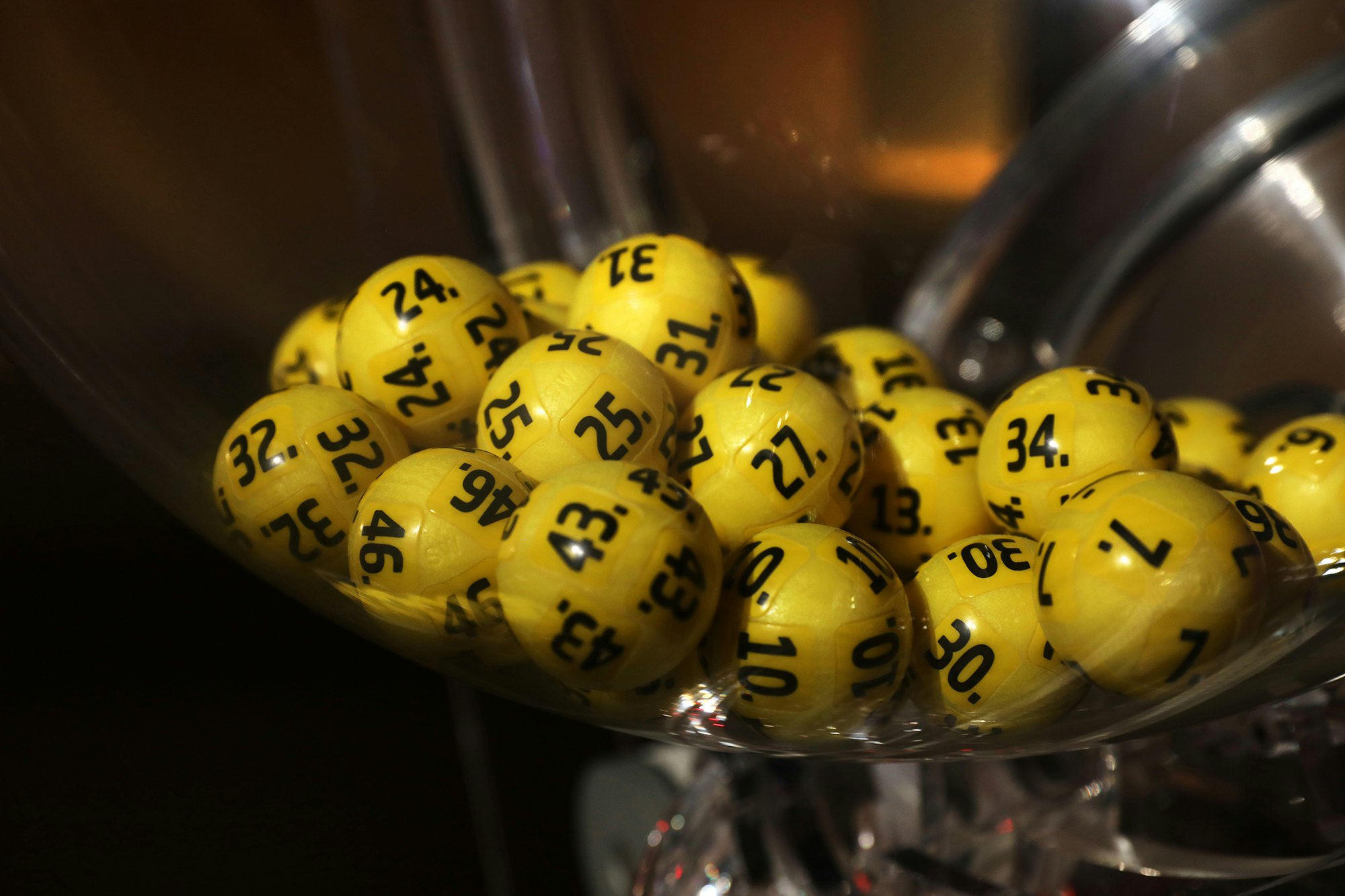 Bilder av lotterikuler i en trekningsmaskin. Gule kuler med sort skrift. Eurojackpot.