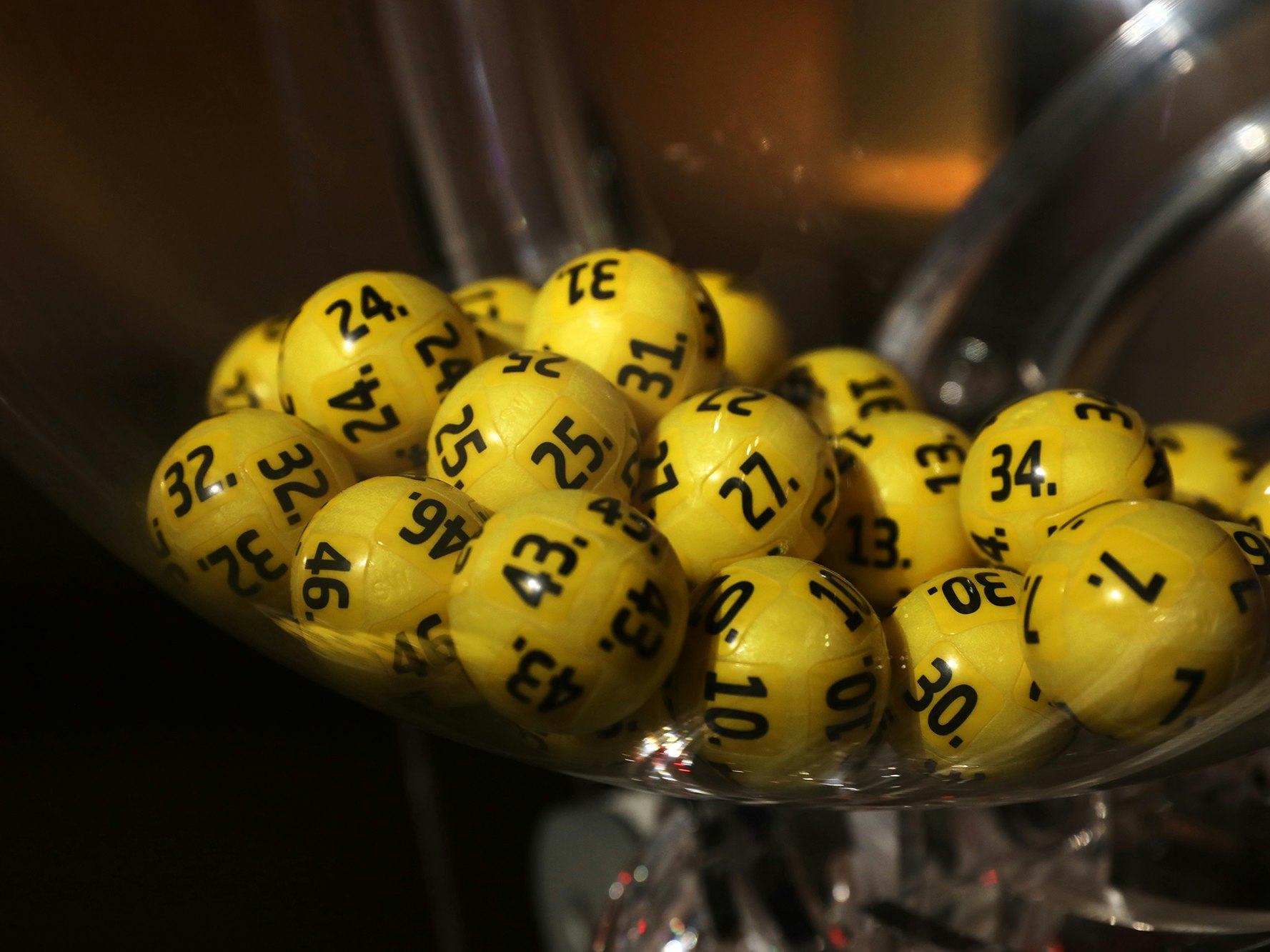 Bilder av lotterikuler i en trekningsmaskin. Gule kuler med sort skrift. Eurojackpot.