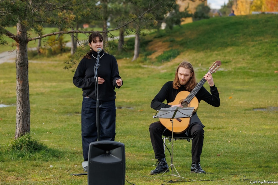 Bilde av to artister, en kvinnelig vokalist og en mannlig gitarist. Utendørs.