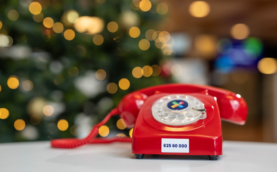 Foto av en rød telefon med utydelig juletre i bakgrunnen