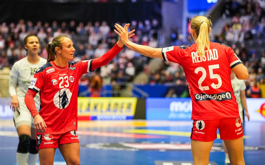 Bilde av to kvinnelige landslagsspillere i håndball som gjør "high five" på banen.