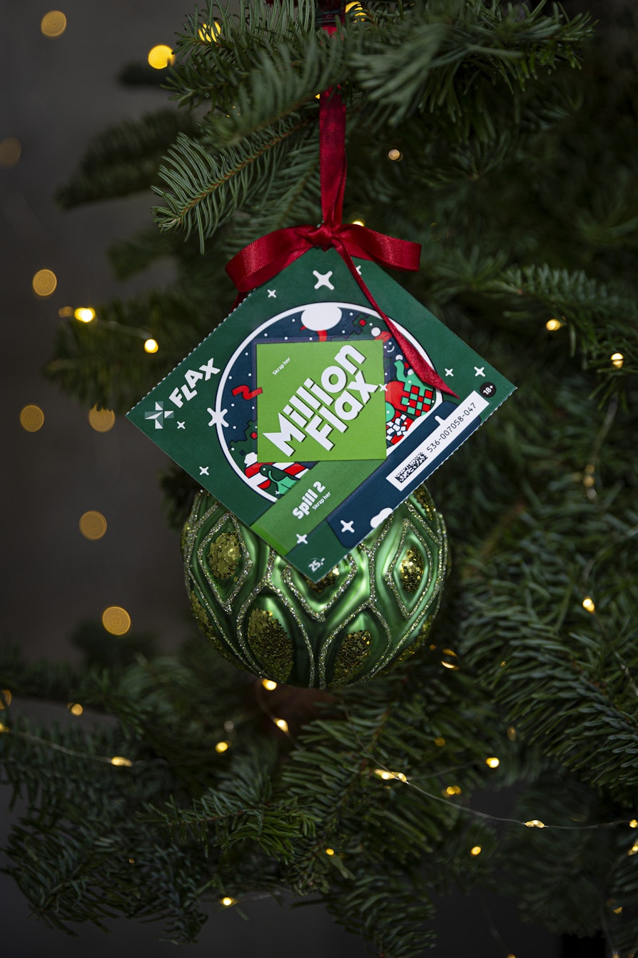 Et MillionFlax-lodd henger sammen med en grønn julekule på en juletregrein.