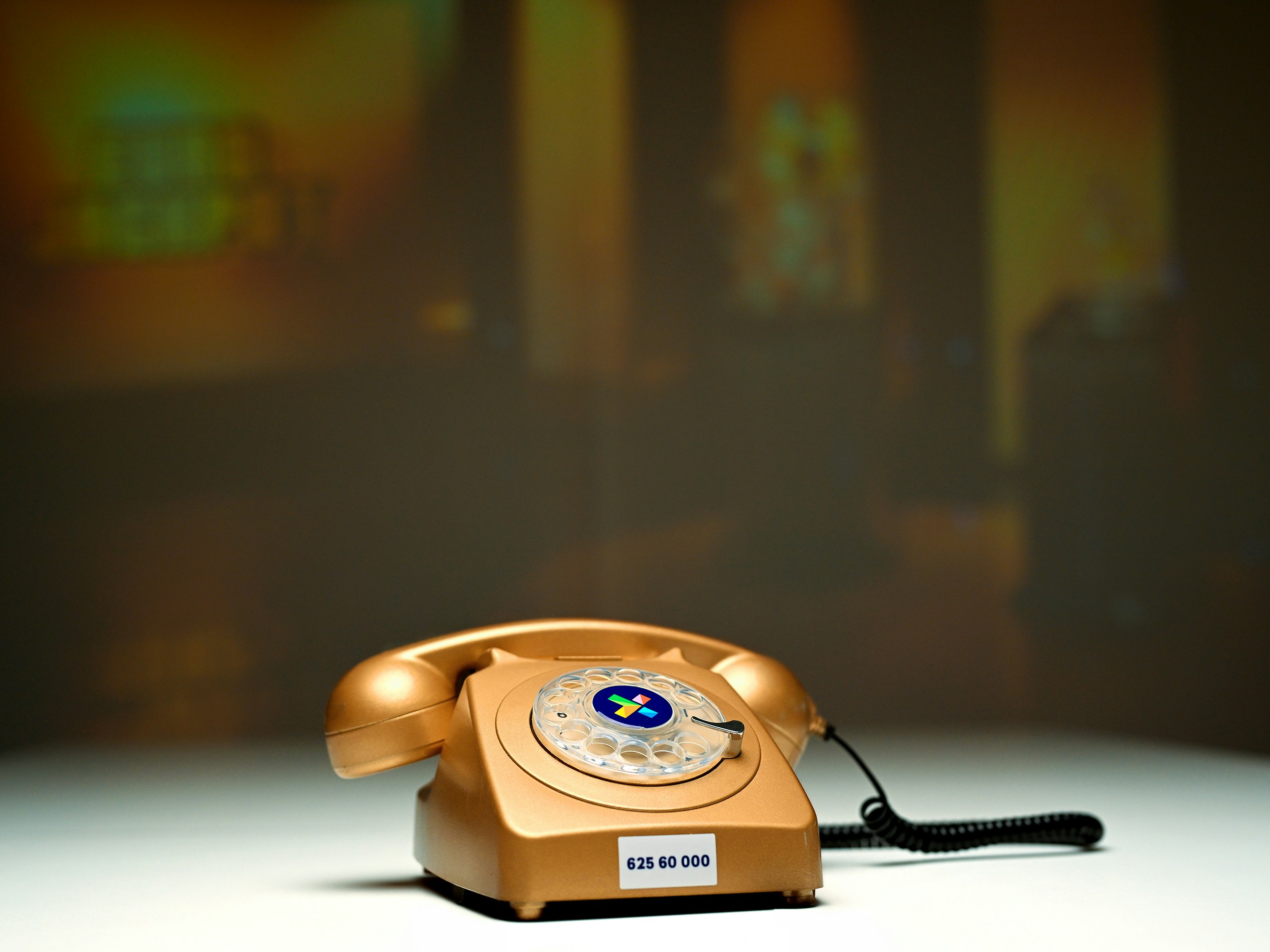 Bilde av gammeldags telefon i gullfarge. Står på et bord. Bak et lerret med Eurojackpot-logo.