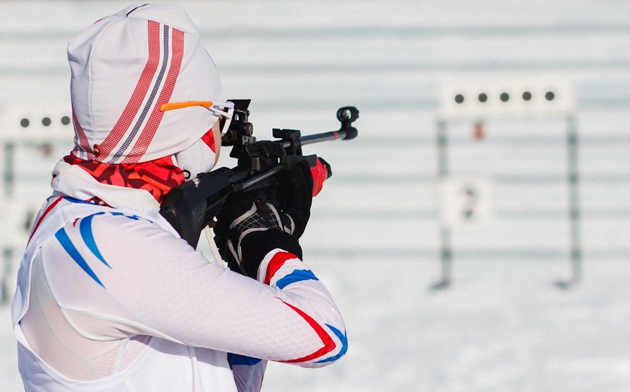 Bilde av en skiskytter på standplass. Bildet tatt bakfra.