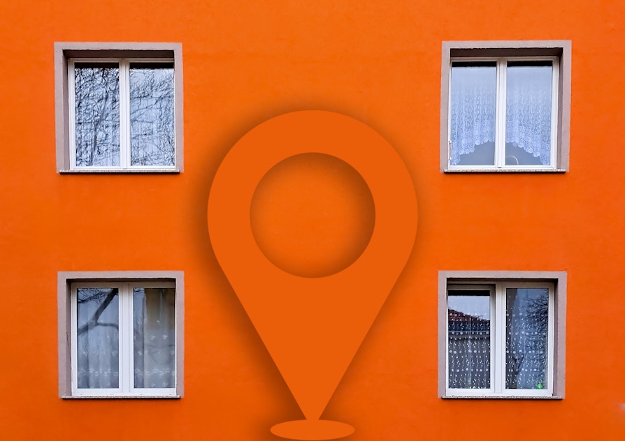 Bilde av en boligblokk. Bilde tatt tett på. Viser fire vinduer over to etasjer. Oransje farge. I midten av bildet er geotagen kjent fra Nabolaget limt inn.