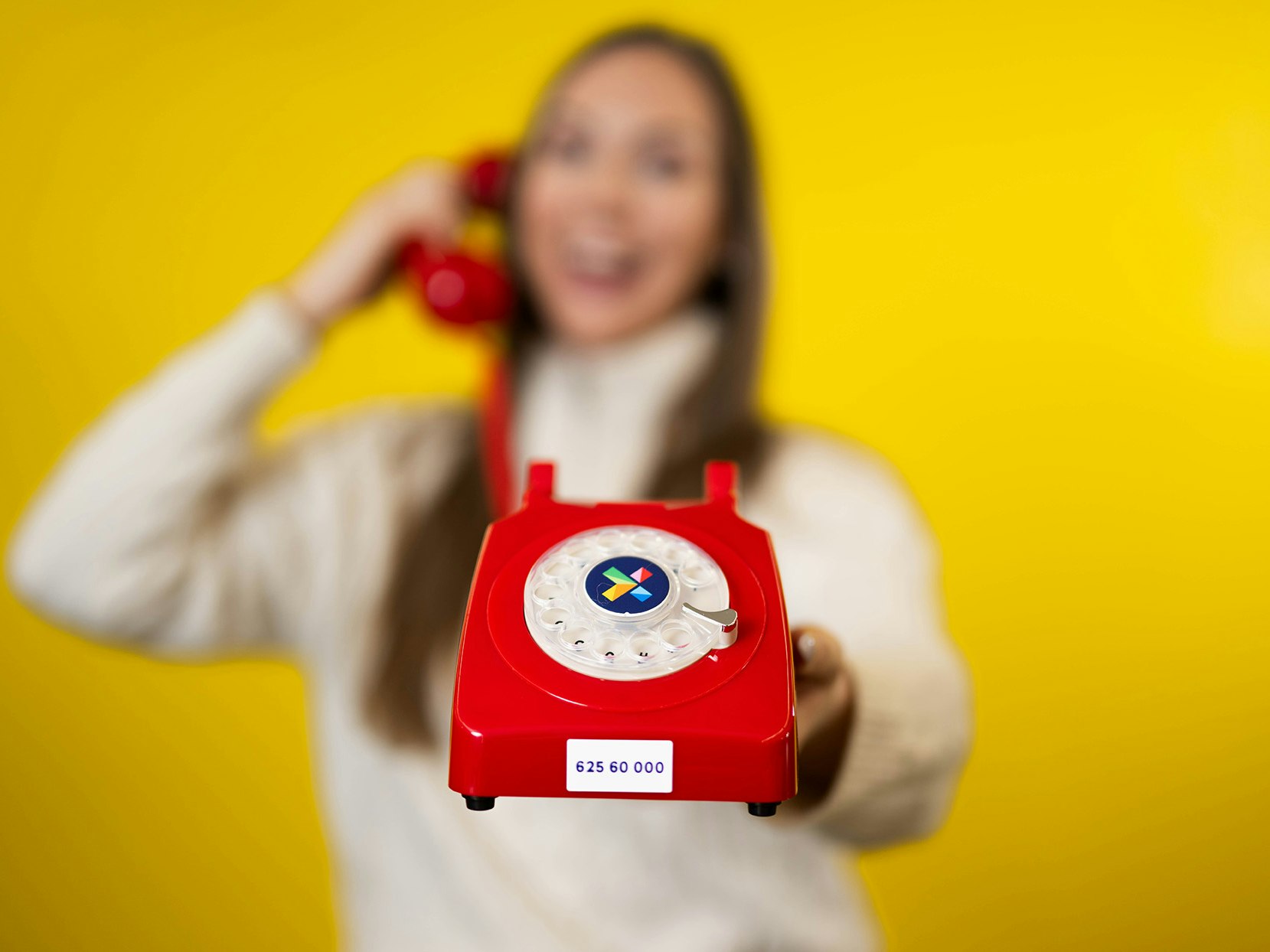 Kvinne holder i rød telefon med Norsk Tippings vinnernummer på. Supertrekning påske 2024.