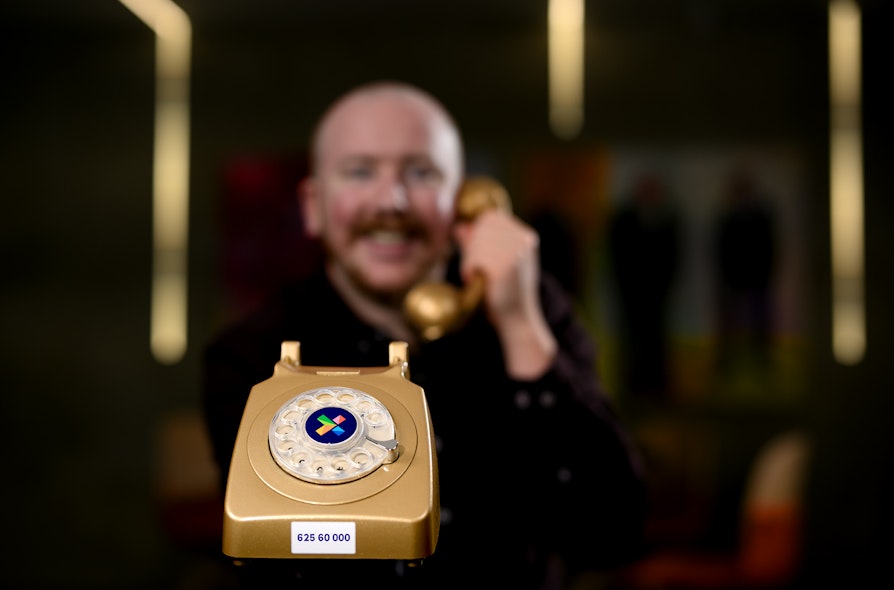 Bilde av en uskarp person som holder et gammeldags telefonapparat i gullfarge. Eurojackpot fra Norsk Tipping.
