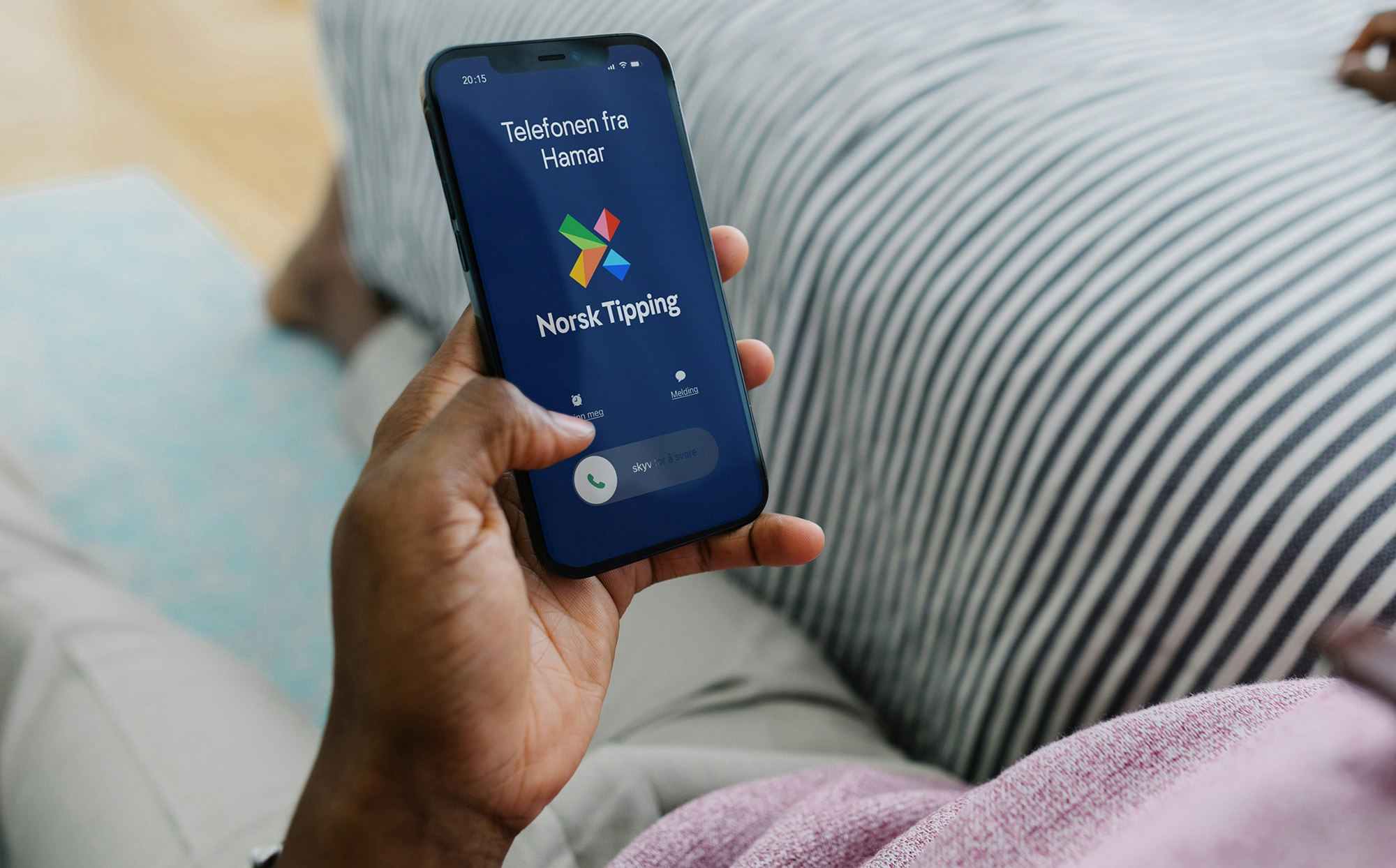 Mann holder en telefon hvor Norsk Tipping ringer
