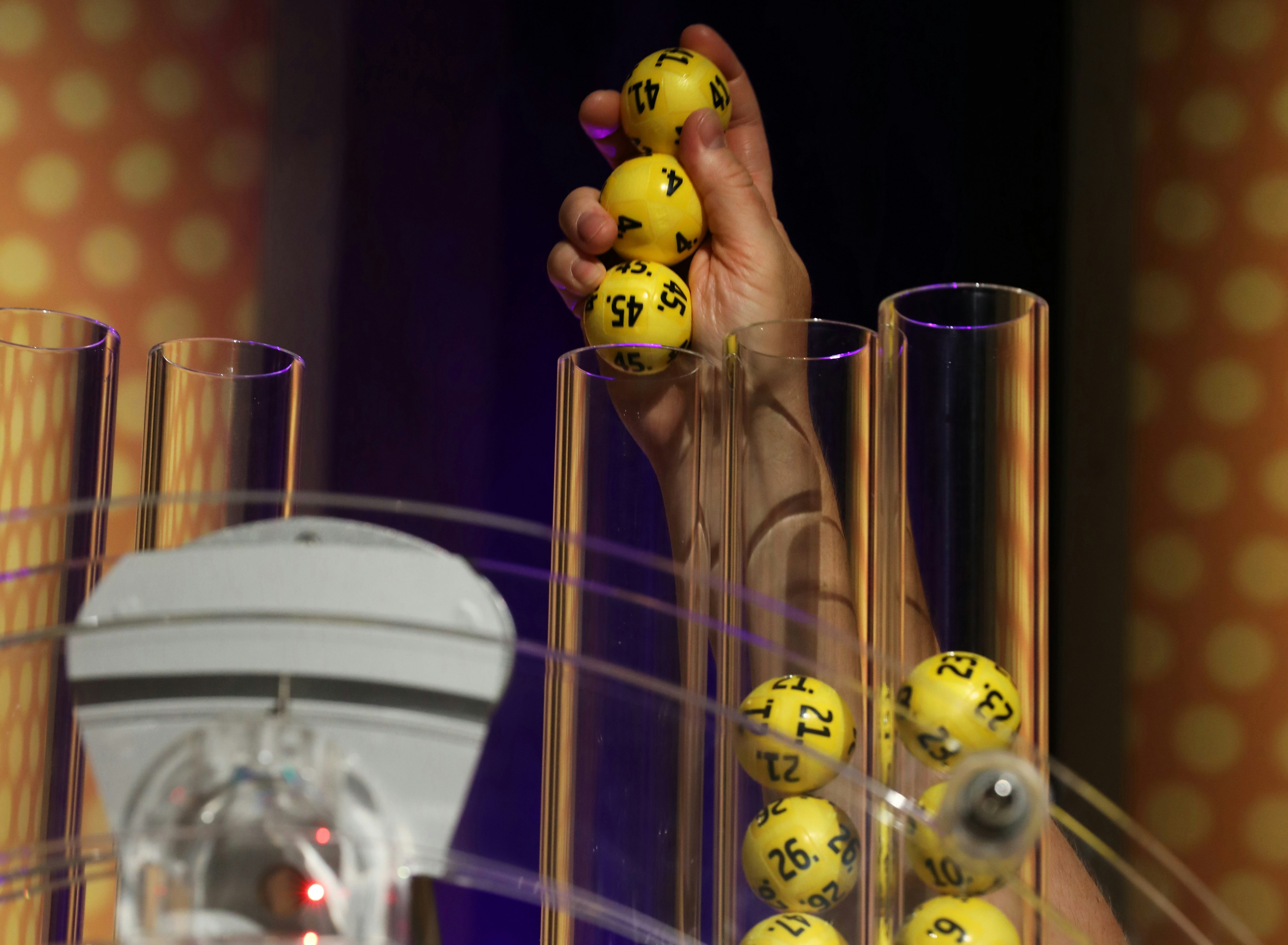 Bilde av en person som legger kuler klar til å trekkes av en trekningsmaskin for Eurojackpot. Bilde tatt i tv-studio.