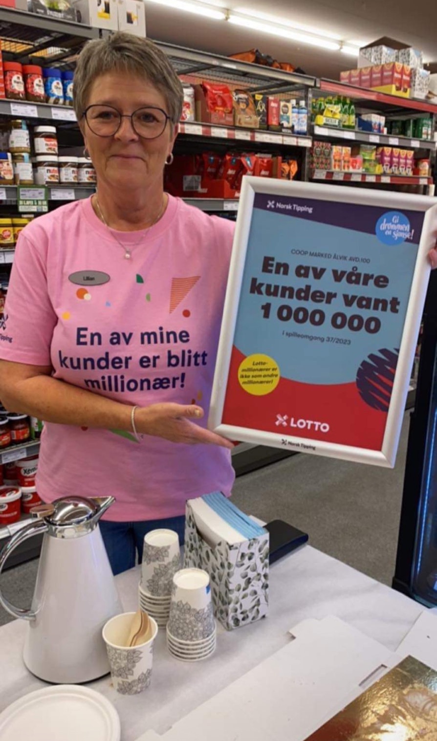 Supertrekning-vinner Lillian Aga med plakaten av at butikken har solgt en kupong til en Lotto-millionær.