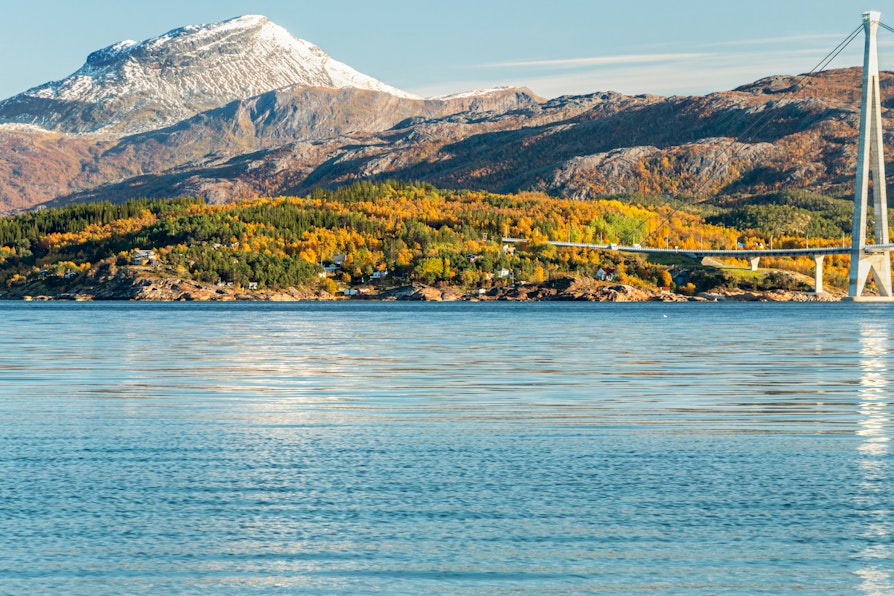 Utsikt over Rombaksfjorden i Narvik over til Halogaland bro med høstfarger og snøkledde fjell i bakgrunnen.