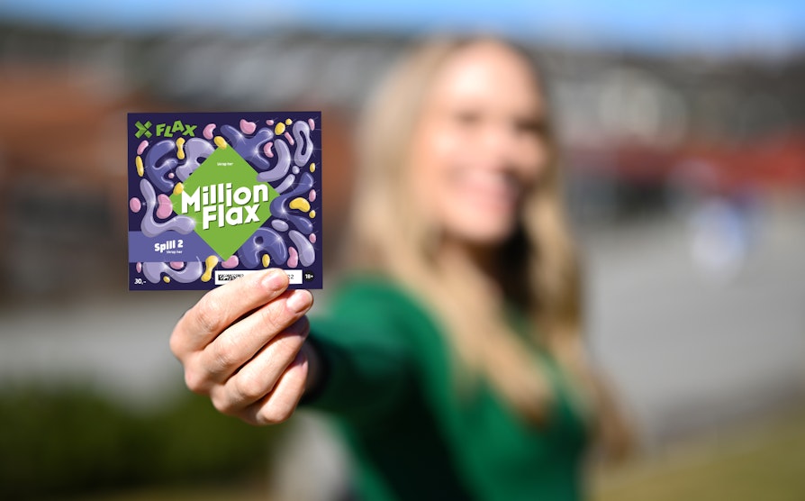 Kvinne i ufokus i grønn ganser og blondt langt hår, holder opp et lilla mønstret MillionFlax mot kamera.