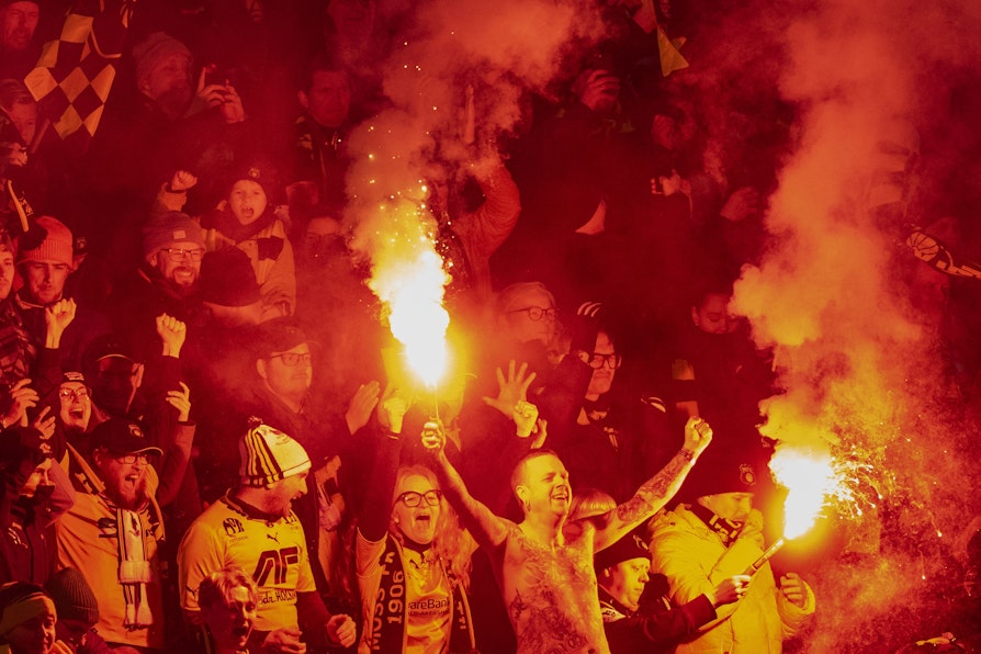 Bilde av Moss fotball-supportere på tribunen. Bluss og god stemning.