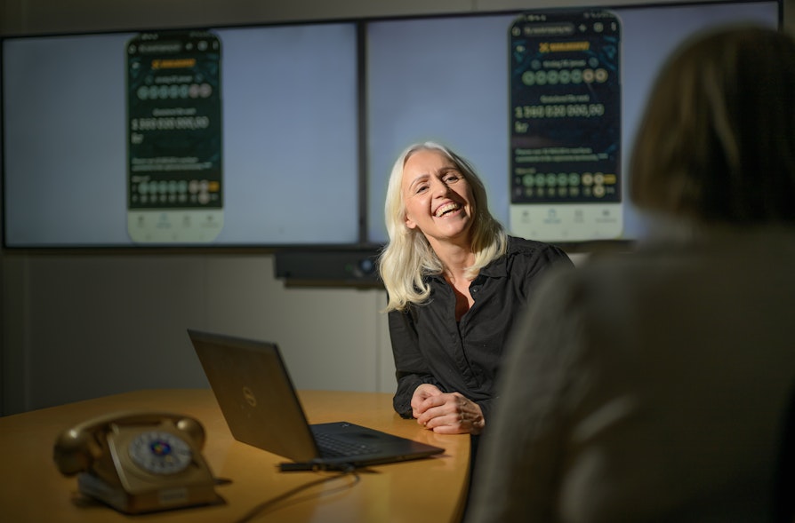 Østlandskvinnen som vant 1,36 milliarder kroner i Eurojackpot i samtale med lotteri- og trekningsansvarlig Ingrid Roterud Mathisen i Norsk Tipping. Kvinnen er anonymisert på bildet, fotografert bakfra. Bildet er tatt i et møterom i Norsk Tippings lokaler på Hamar.