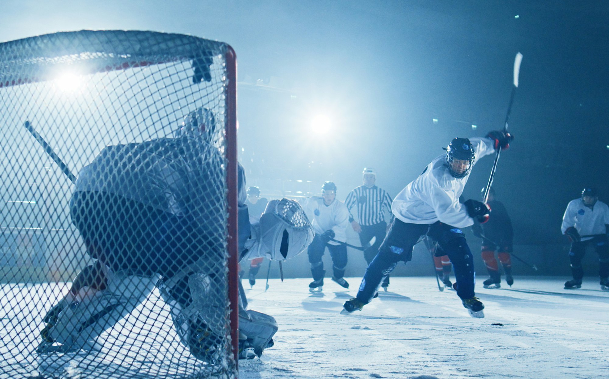 Hockey-spillere ute på isen. Hockey-spiller skyter pucken på mål. Brukt til Grasrot