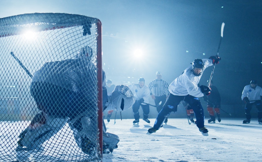 Hockey-spillere ute på isen. Hockey-spiller skyter pucken på mål. Brukt til Grasrot
