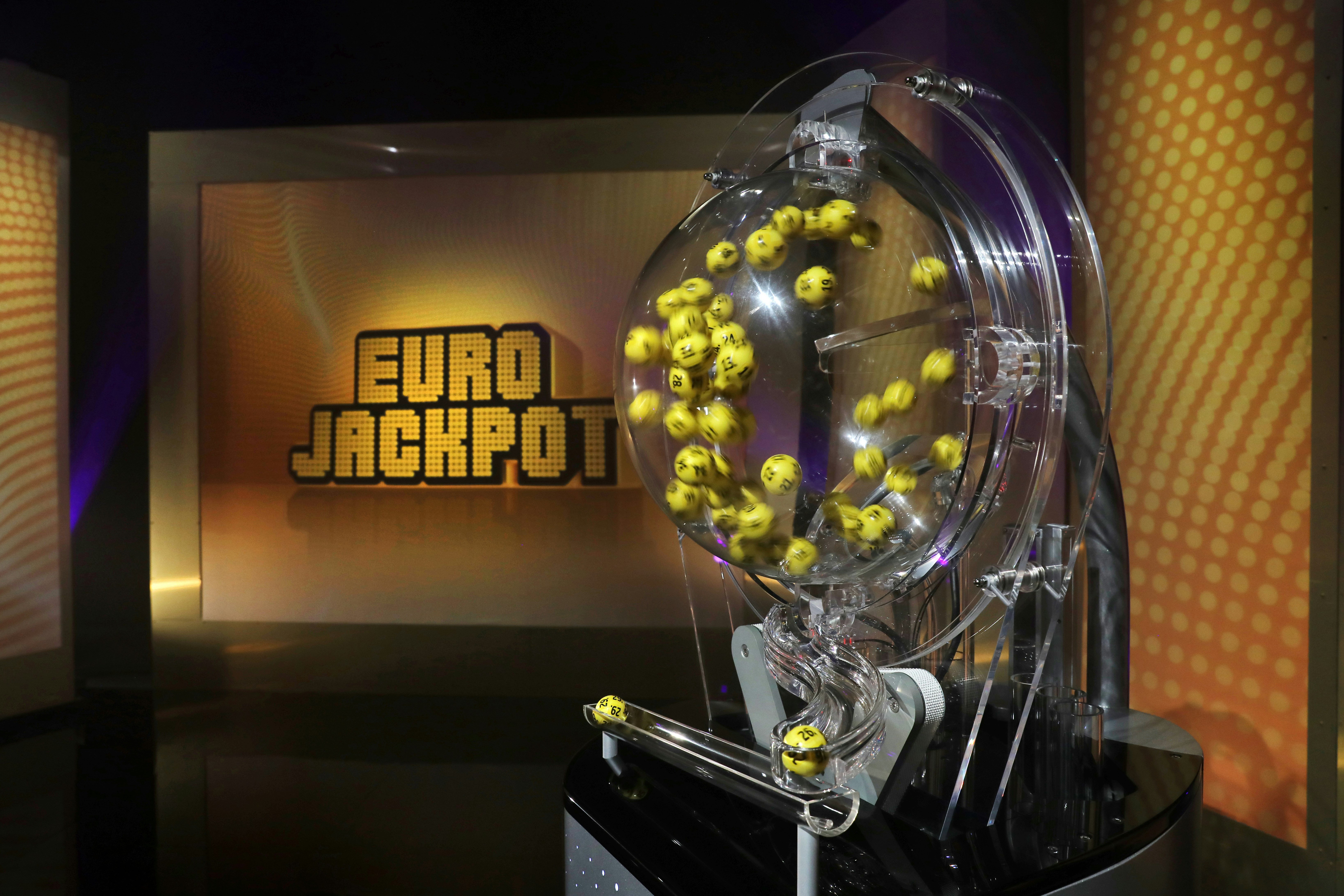 BIlde av trekningsmaskinen i Eurojackpot. Bilde tatt i tv-studioet i Helsinki, Finland. Baller fyker rundt i maskinen, som står plassert foran en vegg med Eurojackpot-logo.