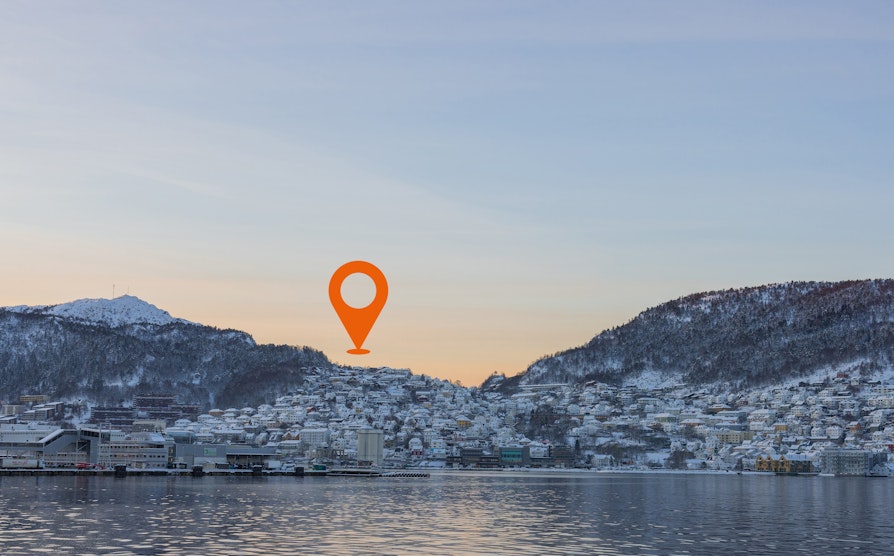 Utsikt fra vannet mot Laksevåg i vintermorgensol, med Nabolagets geotag i horisonten.