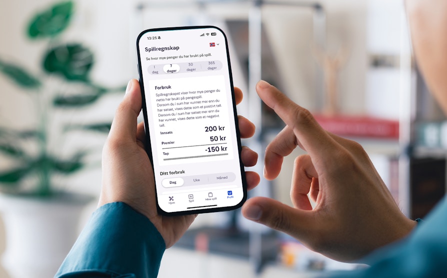 Hender holder opp mobil som viser spillregnskapet inne i Norsk Tipping-appen