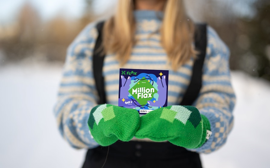 Utsnitt av en kvinnetorso med grønne votter, blå strikkegenser og blondt hår som holder et MillionFlax med begge hender.