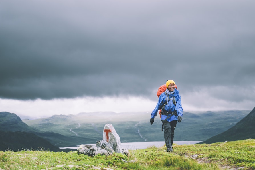 En dame med turutstyr går tur i fjellheimen.