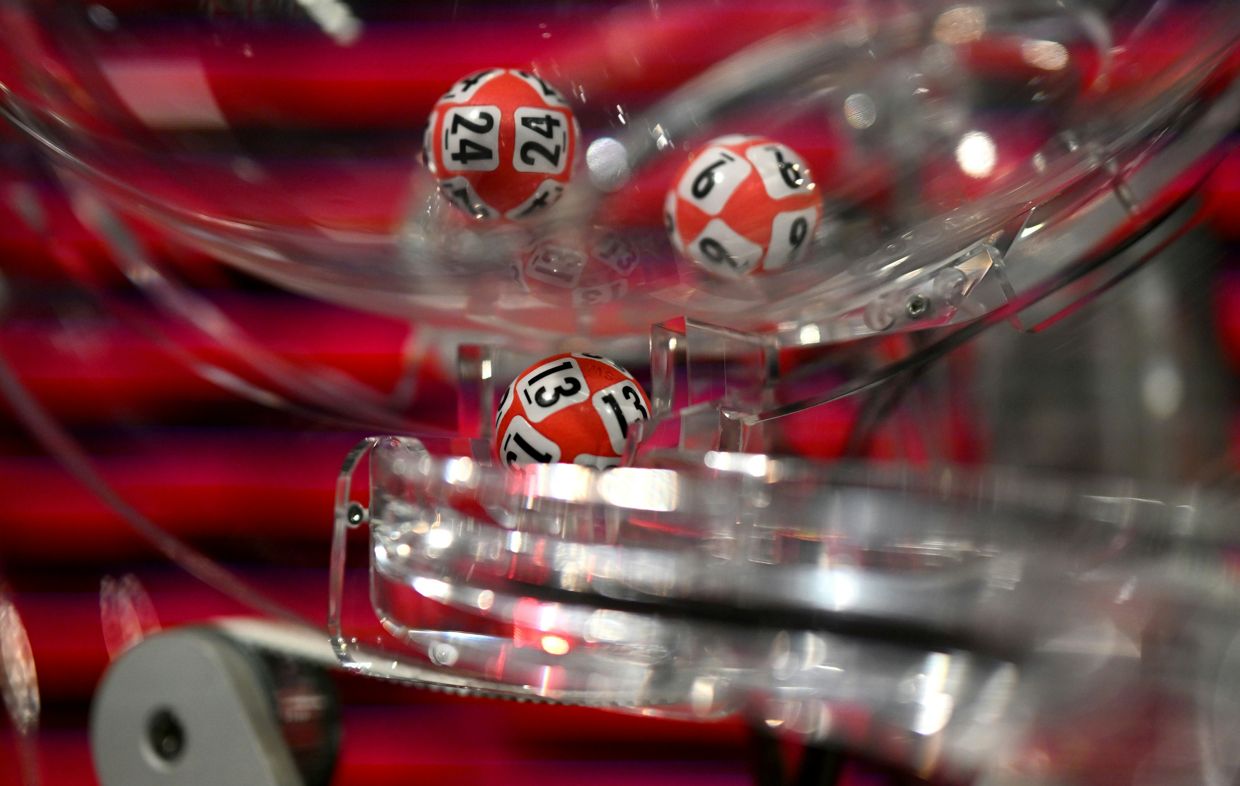 Bilde av trekningsmaskin Lotto. Bilde tatt tett på, man ser tre kuler inne i maskinen.