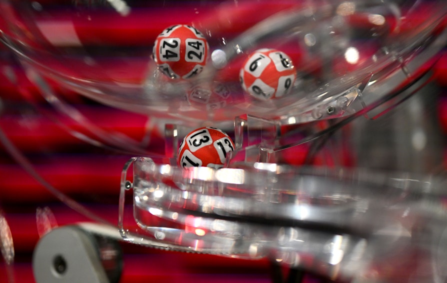 Bilde av trekningsmaskin Lotto. Bilde tatt tett på, man ser tre kuler inne i maskinen.