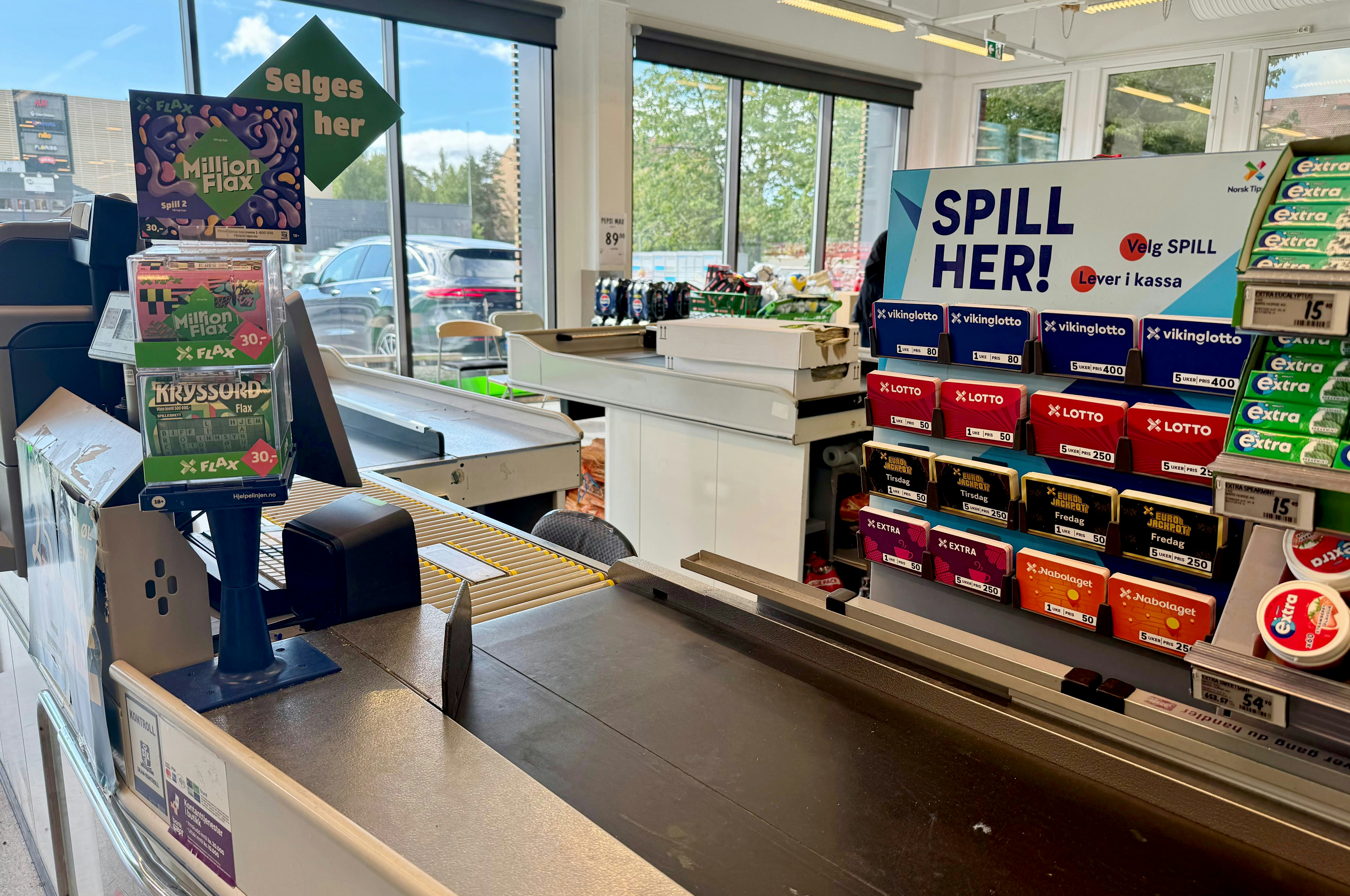 Bilde av en kasse i en dagligvarebutikk. Viser lotterispill og Flax-dispenser.