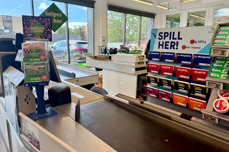 Bilde av en kasse i en dagligvarebutikk. Viser lotterispill og Flax-dispenser.