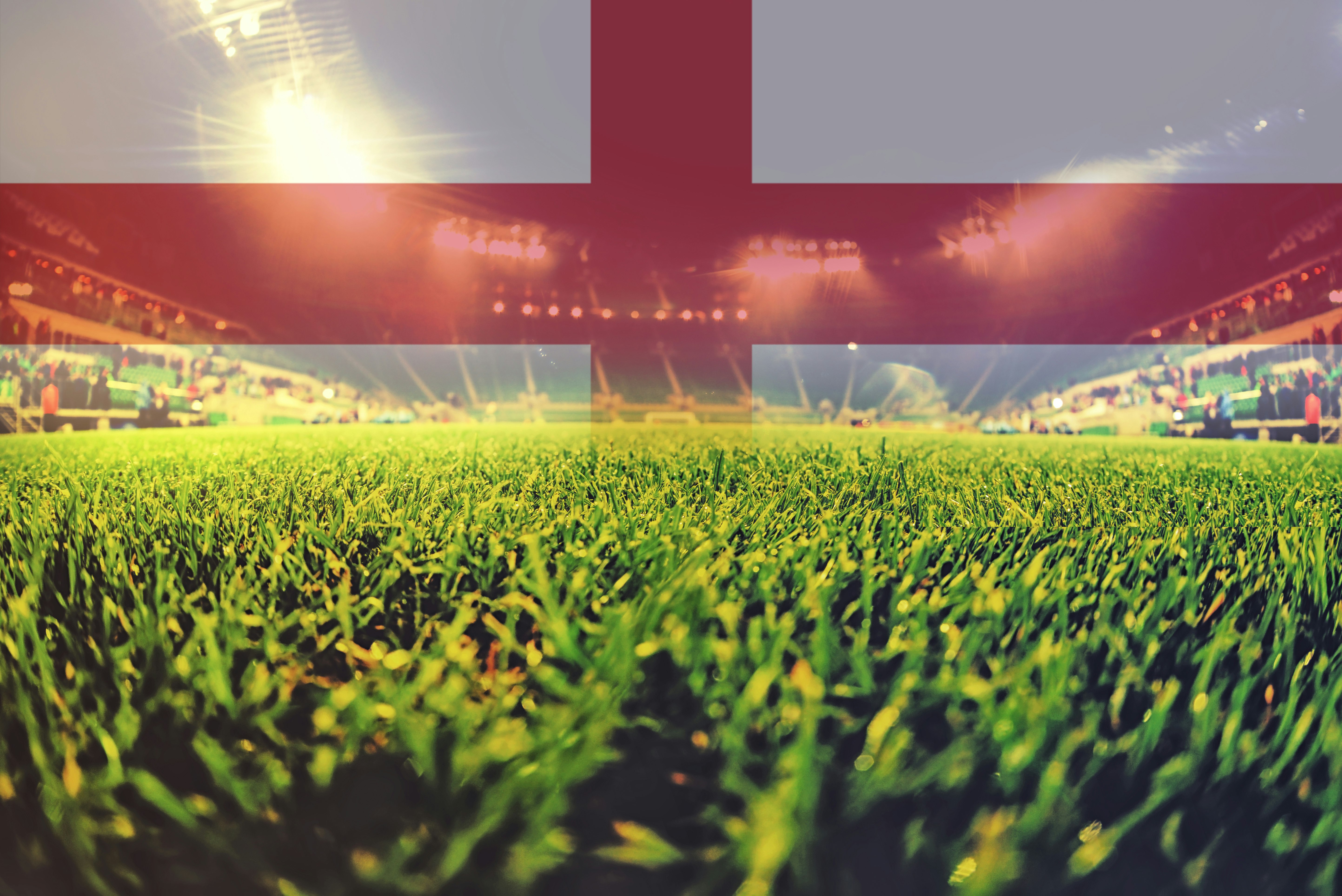 Illustrasjon av en fotballarena. Tett på gresset. Engelsk flagg i bakgrunnen.