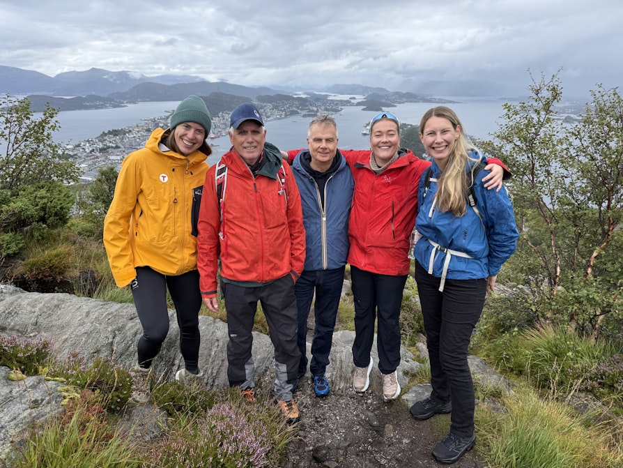 Fem turgåere står på toppen av et fjell og har sjø og øyer i bakgrunnen.