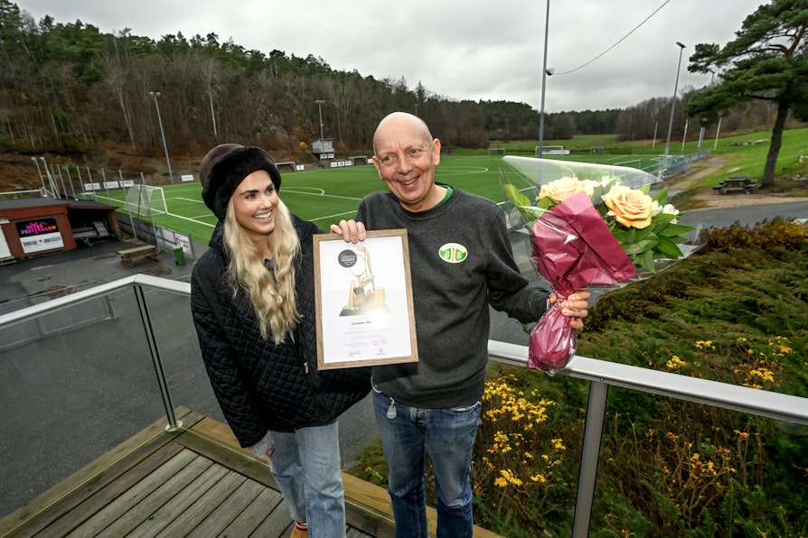 BLE GODT LURT: Sigmund ble innkalt til et møte på klubbhuset. Midt i møtet dukket Norsk Tipping, Norges idrettsforbund og Silje Norendal opp med pris.  Bilde av Norendal og Karlsen utenfor klubbhuset, med fotballbane i bakgrunnen.