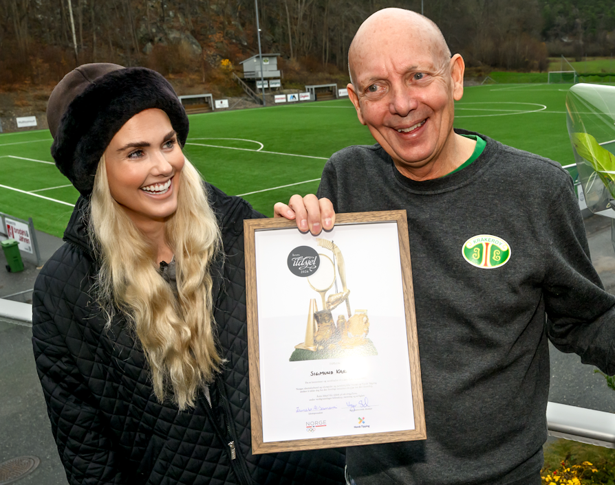 OVERRASKET: Sigmund Karlsen i Kråkerøy IL overraskes med prisen «Årets ildsjel» for Viken idrettskrets 2026. Her er de to fotografert på Kråkerøy stadion etter overrekkelsen.