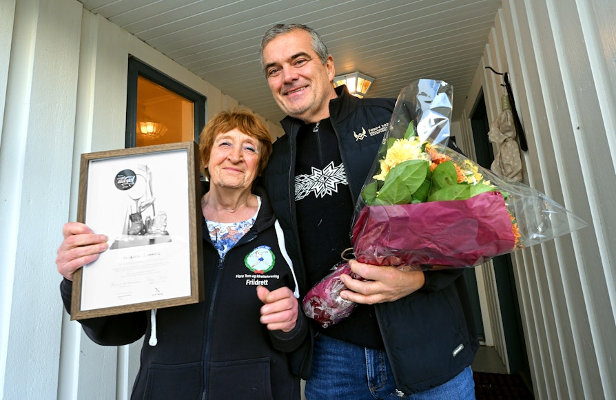 Annbjørg Russavik og Stian Grimseth fotografert med diplom og blomst utenfor inngangsdøra.