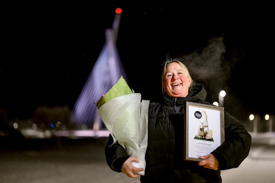 Lise Marianne Johansen stårforan Tana bru. Mørkt rundt. Vinter. Kaldt.