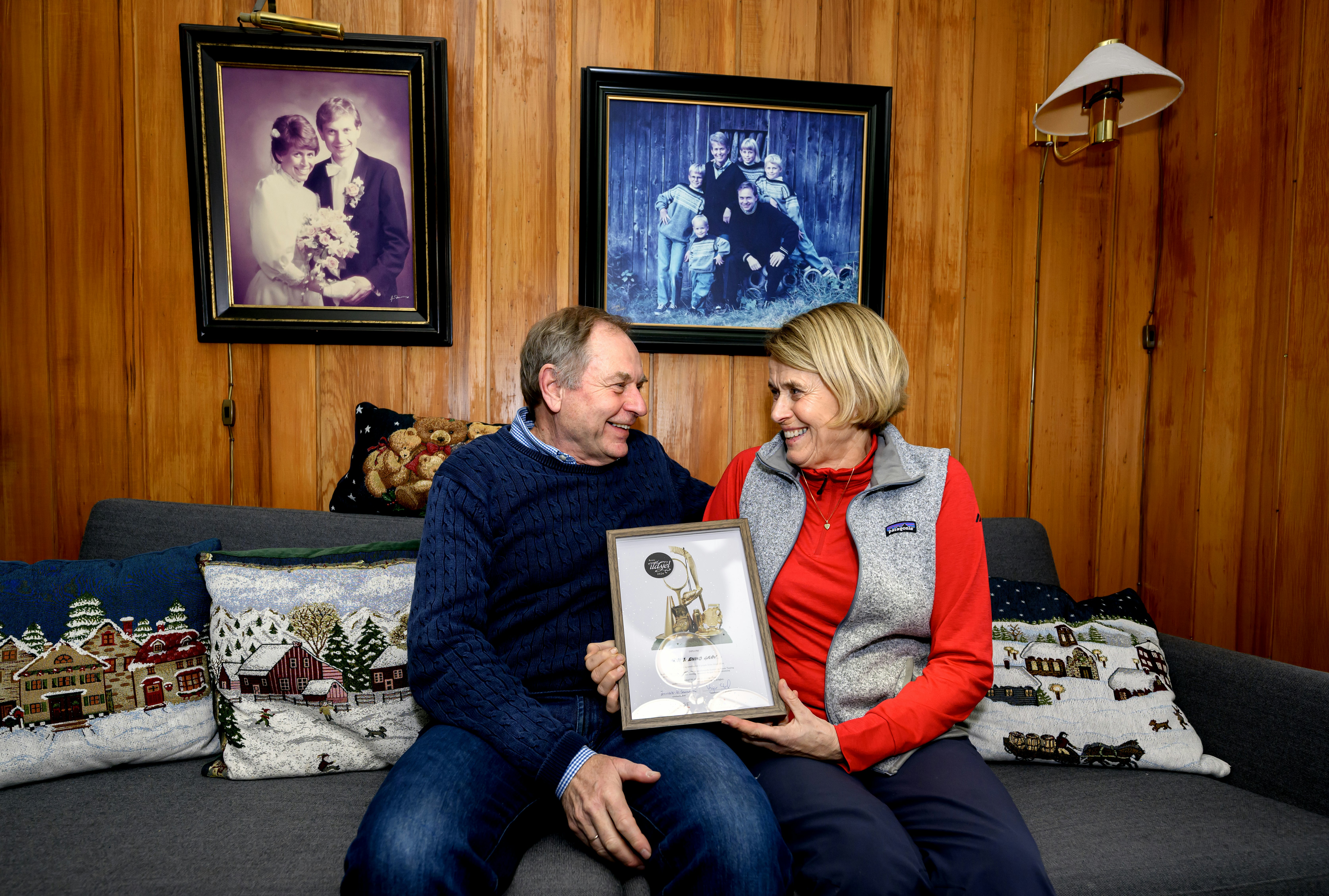 Eivind Grøv og kona Heidi Sørum Grøv (Byaasen Skiklub) er kretsvinnere fra Trøndelag til Ildsjelprisen 2026. Her sitter de sammen i soafen hjemme, med diplomet mellom seg.  Foto: Ola Thorset, Norsk Tipping)