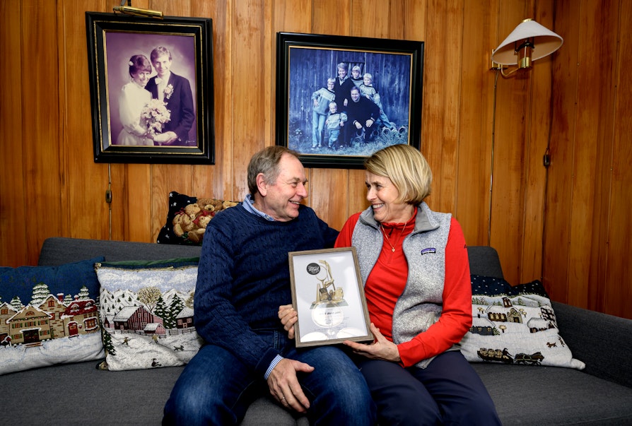 Eivind Grøv og kona Heidi Sørum Grøv (Byaasen Skiklub) er kretsvinnere fra Trøndelag til Ildsjelprisen 2026. Her sitter de sammen i soafen hjemme, med diplomet mellom seg.  Foto: Ola Thorset, Norsk Tipping)