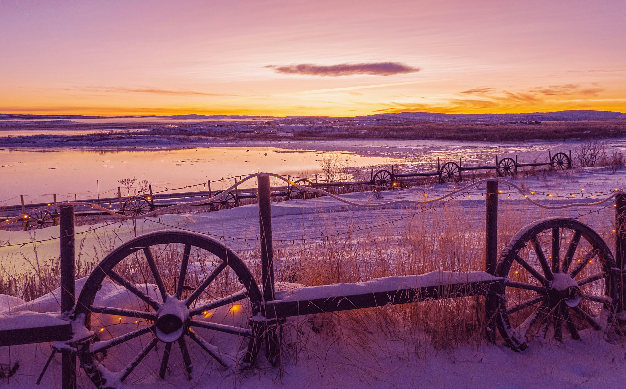 Snø på gjerde og jorde med et lite vann og fin himmel i bakgrunnen i Varangerbotn, Finnmark. Lilla farger. Extra.